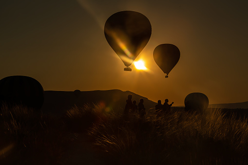 A crew standing in between the two partially filled hot air balloon or a newly inflated balloon in the morning darkness at the cappadocia in Turkey