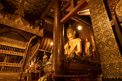Huge seated golden Buddha statue inside Wat Xieng Thong temple in Luang Prabang, Laos