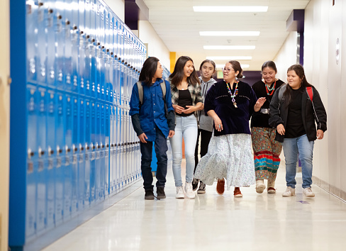 Teacher walking among a group of students while walking at school