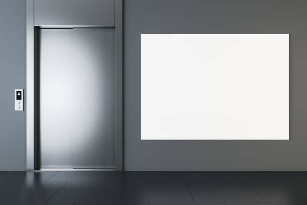 istock Front view on blank white big poster with place for your logo or text on dark grey wall in modern office hall with metallic lift entrance and dark glossy floor. 3D rendering, mockup 1443968106