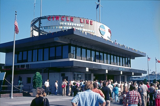 New York City, NY, USA, 1975. The Circle Line Sightseeing Tours Pavilion at Pier 83 in New York City. Also: Tourists who want to buy a ticket for a tour boat.
