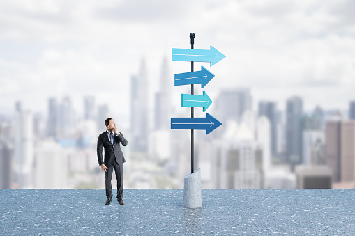 A businessman runs past a large arrow pointing the way.