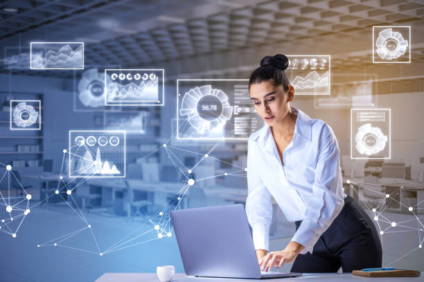 Portrait of attractive thoughtful young european businesswoman using laptop while standing at desk in toned office interior with glowing business charts. Statistics, Growth and Analysis Information concept. Double exposure retrato de una atractiva joven empresaria europea reflexiva que usa una computadora portátil mientras está de pie en el escritorio en el interior de una oficina tonificada con brillantes gráficos de negocios. estadística, crecimiento y análisis concep