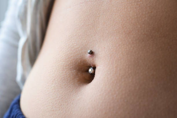 nahaufnahme beim bauchnabelpiercing - piercing stock-fotos und bilder