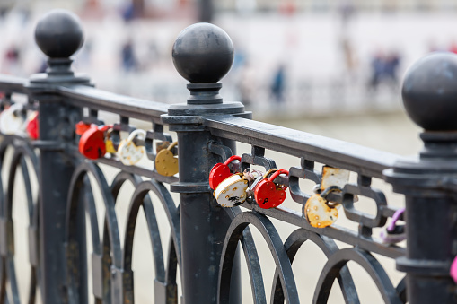 Heart-shaped padlock hanging on a bridge. White, gold and red love lock. Wedding tradition. Locks on the bridge. Valentine's Day background.