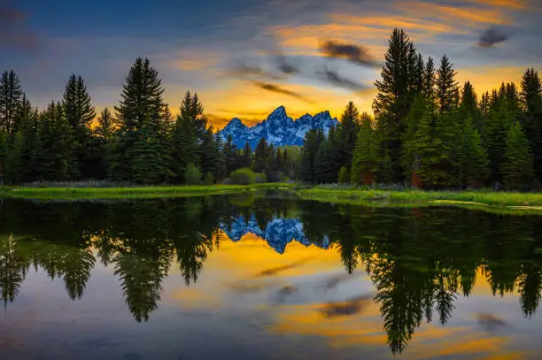 Sunset over Schwabacher Landing with Teton Mountain Range reflected in the waters of Snake River in Wyoming, USA.