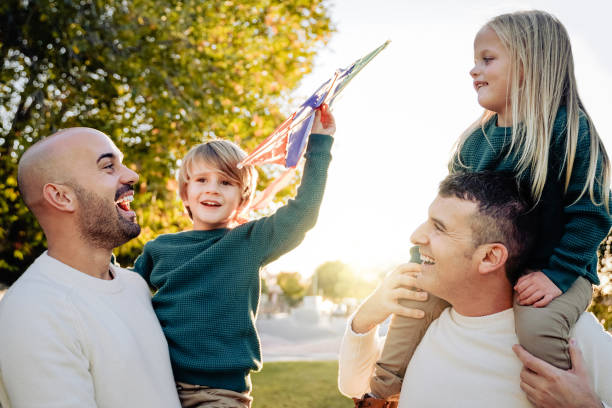 Gay fathers and children playing together with kite outdoor - LGBT family love concept - Focus on left dad face Gay fathers and children playing together with kite outdoor - LGBT family love concept - Focus on left dad face. gay daddy stock pictures, royalty-free photos & images