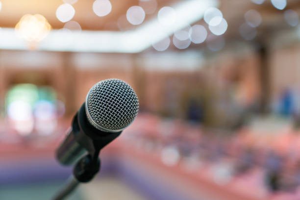 istock Public Microphone for speech speaking in seminar hall on blure backgrounds, Close-up  microphones on stand for speaker teaching room with Event light convention hall for Business meeting education 1443980044
