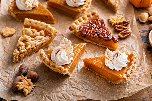 Thanksgiving pies slices on parchment paper, pumpkin and pecan pie