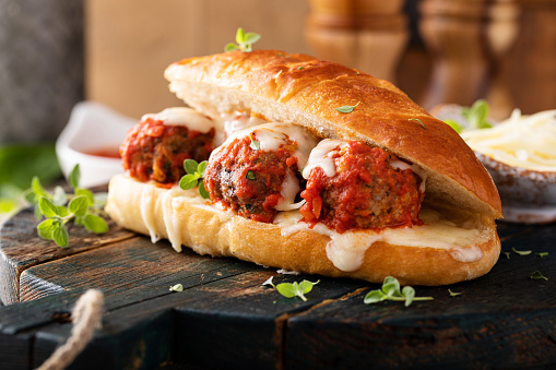 Meatball sub sandwich with marinara and mozzarella and fresh herbs