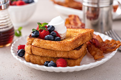 Classic french toast with bacon and fresh berries topped with whipped cream