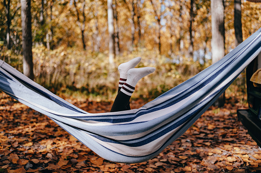 Unrecognizable girl lying down in a hammock while camping in nature.