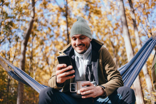 istock Low Angle View Of Happy Man Using A Mobile Phone While Relaxing In A Hammock 1443998195