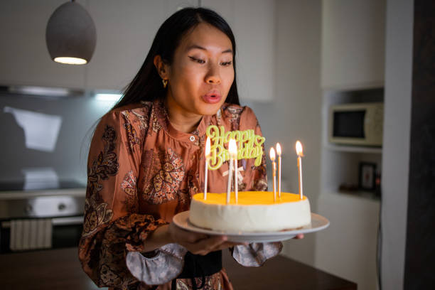 istock Woman blowing out birthday cake candles 1443999580