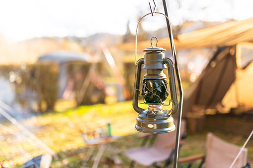 A retro style lantern hanging outside of camping tent area.