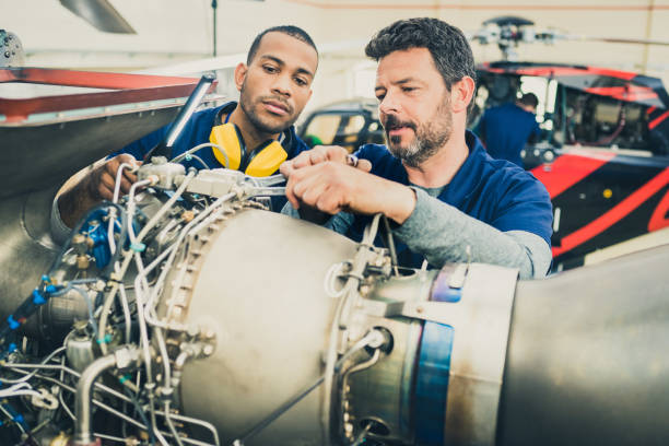 istock Smiling aircraft mechanic teaching coworker examining helicopter engine 1444003841