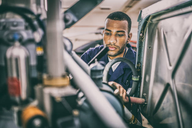 Young male helicopter maintenance technician repairing jet engine, close view. African American aircraft mechanic inspecting and repairing helicopter motor, close up