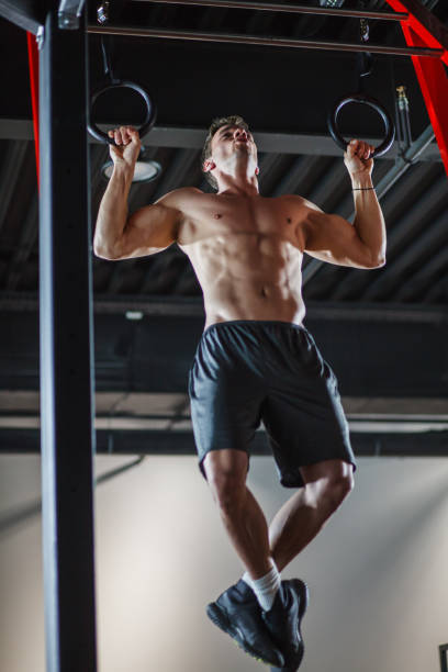 istock Athletic, shirtless young man doing pull ups on gymnastic rings 1444003920
