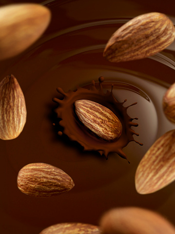 Almonds falling into liquid chocolate
