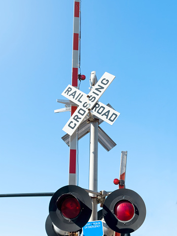 Railroad crossing sign in front of a blue sky