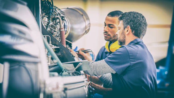 istock Smiling aircraft mechanic teaching coworker examining helicopter engine 1444006299