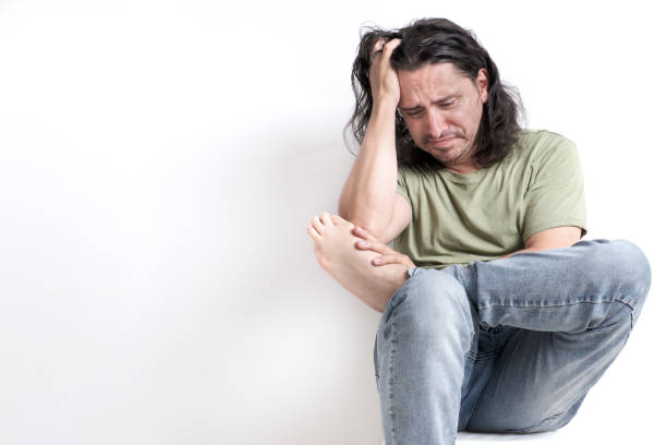 istock middle-aged man sitting anxiously while looking at his amputated finger 1444006475