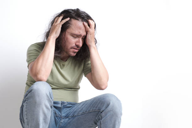 istock an anxious and distressed Latino man clutches his head with both hands and closes his eyes. 1444006525