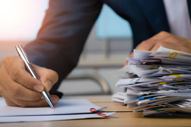 istock Business man hand writing with Stack of Group report papers Document clipped in color clips. 1444007773