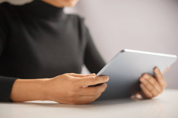 istock Close up of woman hand using tablet to read article instead of printed book. 1444013902