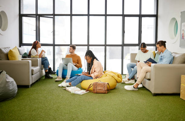 istock Students, diversity and relax study space in school, college or university campus for research support. Business education, learning or technology for friends, men or women with scholarship notebooks 1444021573