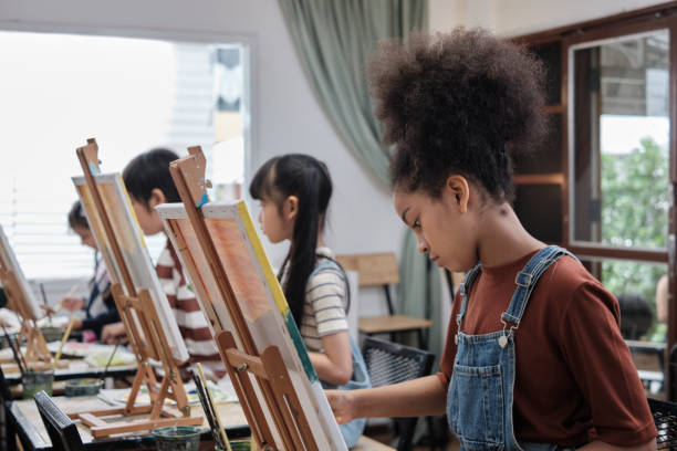 une fille se concentre sur la peinture acrylique sur toile dans une classe d’art. - artist child artists canvas indoors photos et images de collection