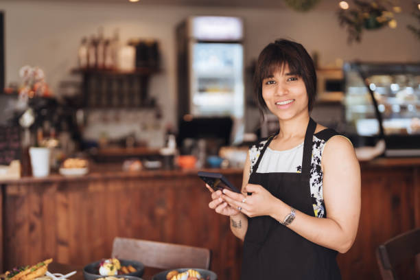 istock Business owner holding smart phone looking at camera. 1444027572
