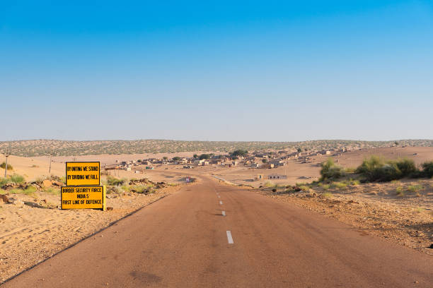 Milestone by BSF, Border security force, beside with empty high road or national high way passing through the desert. Distant horizon, Hot summer at Thar desert, Rajasthan, India. stock photo