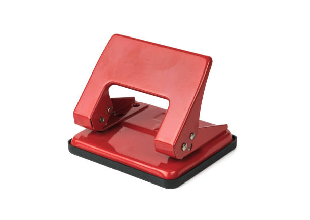 Red metal paper punch isolated on a white background. Minimal stationery concept.