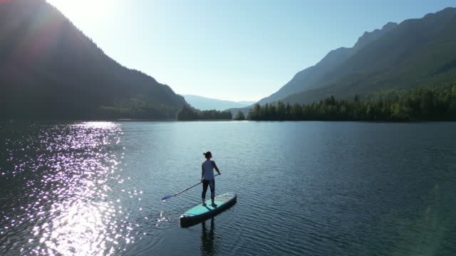 Aerial view of stand up paddle boarder (SUP) enjoying tranquil moments on lake