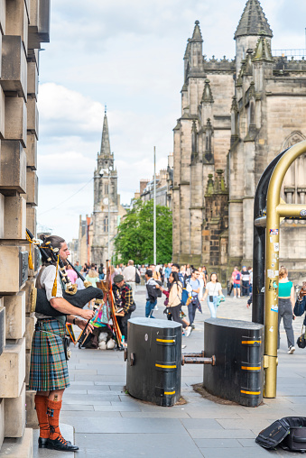 Edinburgh,Scotland-July 30 2022:A Scottish pipe player in traditional Scottish dress,busks for tourists and passers by,next to security barriers,during the summer Fringe festival.
