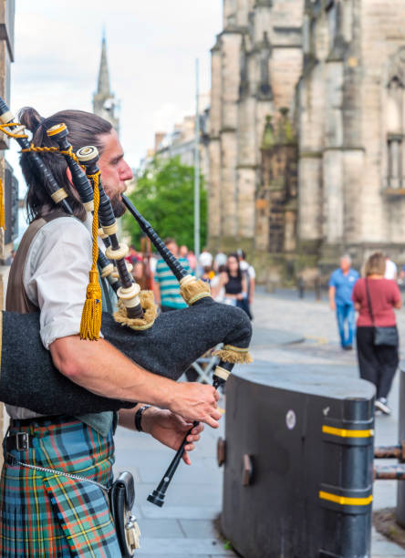 Bagpiper in front of stone cottage with copy-space.
