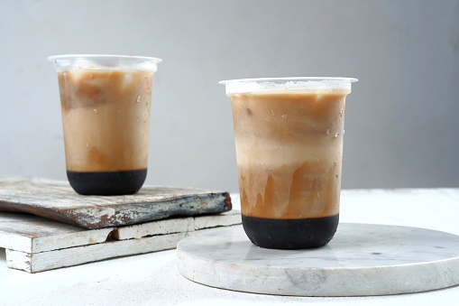 Iced coffee in a plastic cup on white and grey background