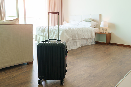 Black Luggage in modern hotel room after door opening. Baggage for Time to travel, service, journey, trip, summer holiday and vacation concepts