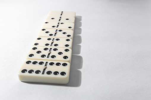 Domino pieces with white background, copy space and various agulos, concept of table games