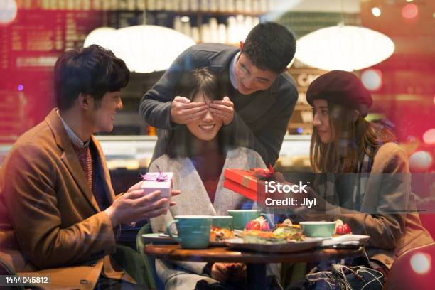 Young East Asians Sitting In A Restaurant Giving Surprise Gifts To Friends In Winter Stock Photo Stock Photo - Download Image Now