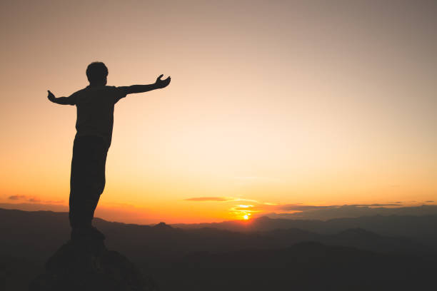 男は山と夕日、自由と旅行の冒険の概念の上に手を上げる。宗教的信念、コピースペース。 - god freedom arms raised high angle view ストックフォトと画像