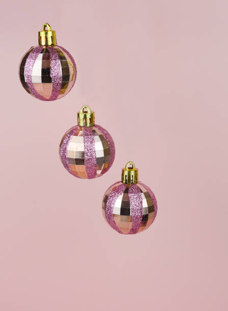 Hanging pink baubles with gitters on pink background. stock photo
