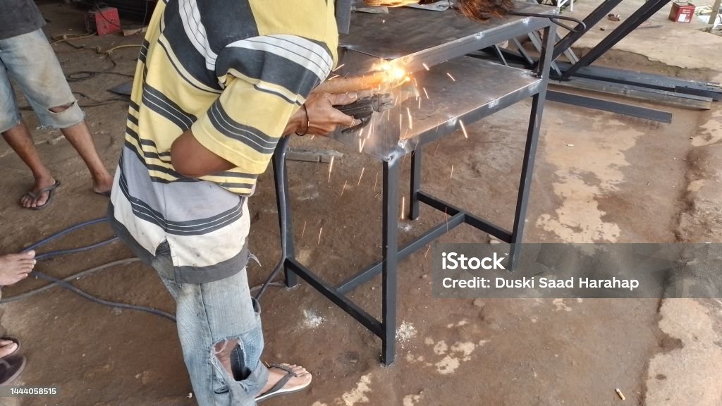 Workers welding iron parts at work with side angle Adult Stock Photo