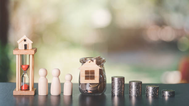 stack of coins, a wooden doll, an hourglass, and a wooden house, all on table,finance and banking, fund growth and savings concept,Planning for savings for the future,building stability for family pila de monedas, una muñeca de madera, un reloj de arena y una casa de madera, todo sobre la mesa, finanzas y banca, concepto de crecimiento y ahorro de fondos, planificación de ahorros para el futuro, construcción de estabilidad para la familia