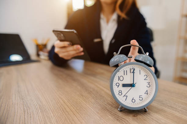 istock Alarm clock on the desk. Business working in modern office building or home at night using laptop. 1444063466