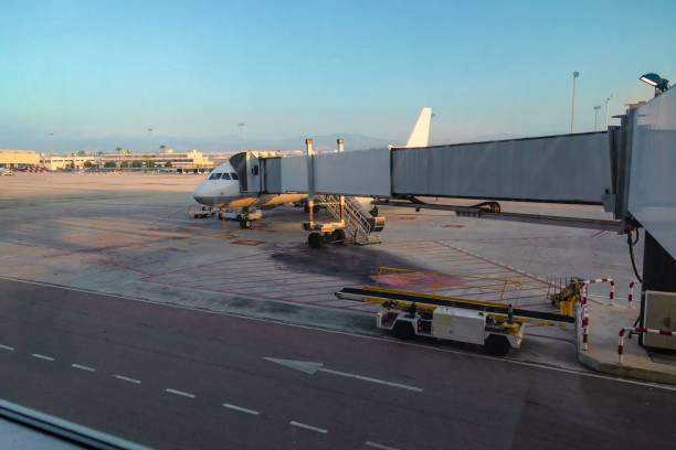 istock Airplane standing on ground with docked passenger bridge for passing for departure or arriving 1444067671