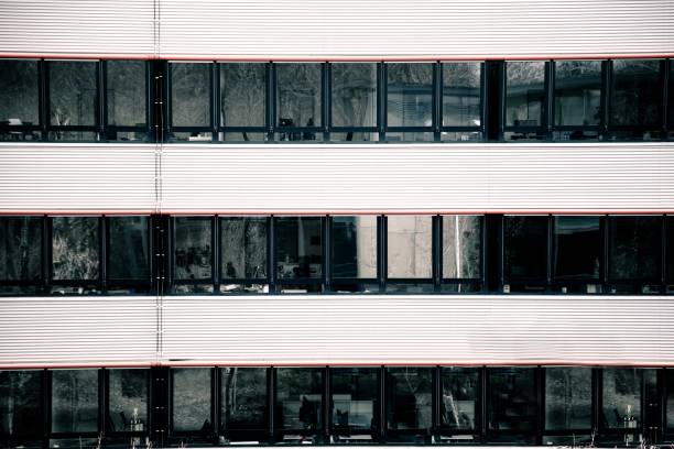 A business building with dark windows with a reflection of trees and empty working spaces