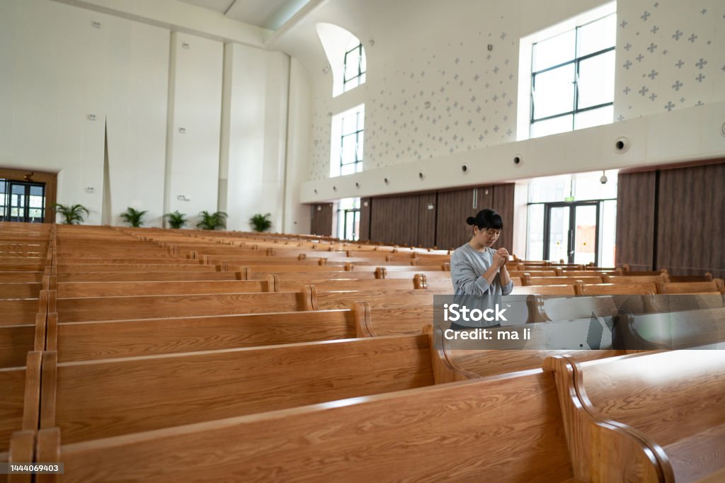 There is only one woman praying in the church Adult Stock Photo