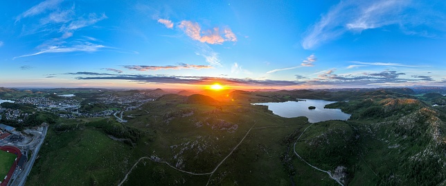 A panoramic shot of a bright orange sunset over rural areas of Norway